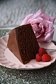 A slice of chocolate cake with raspberries and a rose for Valentine's Day