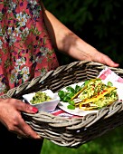 A woman holding a tray of taco shells with guacamole