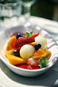 Fruit salad with melon balls and raspberry sauce