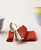 Soup spoons on a stack of red paper napkins
