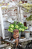 Ornaments on old sewing machine table against garden wall
