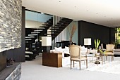 Modern interior with vintage armchairs and modern sofa in front of staircase and black-painted wall in background