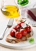A slice of bread topped with with grilled tomatoes and parmesan