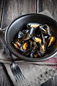 Steamed mussels in a black dish on a linen cloth