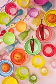 Colourful rows of plastic bowls, spoons and glasses with tangerines and red chillies