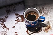 A cup of coffee and ground coffee on a newspaper article
