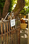 Rusty garden gate with sign warning of dog in French