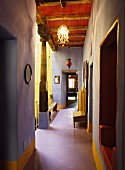 Unusual colour scheme in historical country house with lavender corridor walls, yellow accents and wooden ceiling painted Venetian red