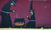 Hexenfiguren mit Kessel an einer Wand im Garten für Halloween
