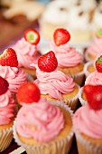 Several cupcakes with strawberry frosting