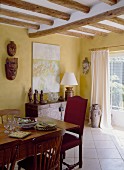 A dining room in an English country house with a wooden table and pieces of art from Nepal and Tibet