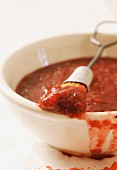 Bowl of spicy plum barbeque sauce with a brush