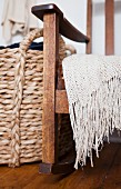 A knitted throw on a rocking chair and a woven laundry bask
