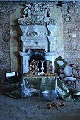Ghost-Stuhl und Tisch mit Weihnachtsdekoration vor offener Kamin mit griechisch antiken Architekturelementen in ruinenhaftem Ambiente