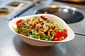Salad leaves with chicken and tomatoes in a restaurant kitchen