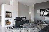 Charcoal armchair with graphic patterns on accessories between modern, free-standing fireplace and flatscreen TV