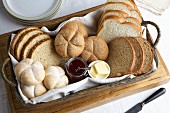 Basket of mixed breads and rolls with jam and butter