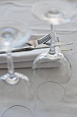 Cutlery on top of a napkin and upturned wine glasses on a table in a restaurant