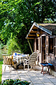 Gartenlaube mit gedecktem Tisch am Wasser im Sommer