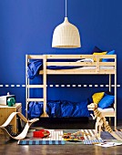 Blue children's bedroom for two - wooden bunk beds, wicker lampshade and wooden toys on woven rug