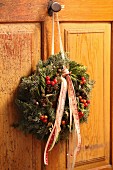 Festive wreath with berries and ribbons hung on cupboard door
