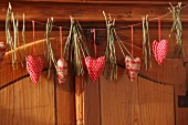Garland of red fabric love-hearts and pine needles hung on cupboard