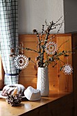 White, crocheted stars hanging from gnarled branch and bundt cake on wood-panelled cabin windowsill