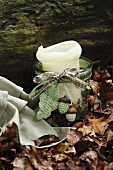 Autumn arrangement in woodland - candle lantern decorated with ribbon and crocheted acorns and leaf