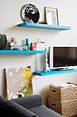 Flatscreen TV on pale blue floating shelf amongst other shelves and home accessories in living area
