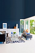 Elegant living room with dark blue wall, woman reading in front of an open terrace door