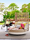 Round designer sofa with headphones in front of a wooden screen on the terrace next to a women's bike and glass fire