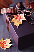 Gift box decorated with ribbon and autumn leaf pendant