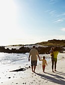 Familie mit zwei kleinen Kindern beim Spaziergang am Meeresstrand