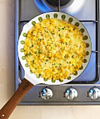 Omelette mit Mais in Pfanne auf Gasherd (Aufsicht)