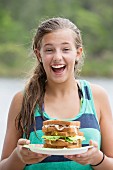 Teenager hält Teller mit mehrstöckigen Sandwich