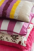 Stack of decorative pillows in assorted pink and purple fabrics