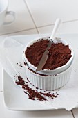 Kakaopulver in weisser Schälchen mit Messer