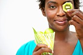 Woman holding kiwi slice in front of eye