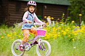 Kleines Mädchen auf einem lila Fahrrad