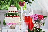Getränke, mehrstöckige Torte & Rosendeko auf Tisch in Gartenpavillon