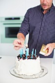 Vater zündet Kerzen auf Torte für 1. Geburtstag an