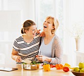Mutter & erwachsene Tochter beim gemeinsamen Kochen in der Küche
