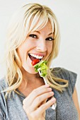 A young woman eating salad from a fork