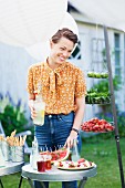 Lächelnde Frau mit Getränk auf Gartenparty