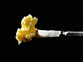 Butter on a knife against a black background