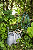 Watering cans and hose in garden