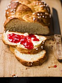Hefezopf (sweet bread from southern Germany), partly sliced with butter and jam