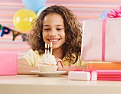 Young girl with cupcake and lit candles at birthday party