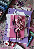 Artistic collection of pictures, notebook, paintbrushes and crocheted flowers tied in bundle with pink velvet ribbon