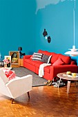 Living room with a feminine touch, blue walls and red sofa